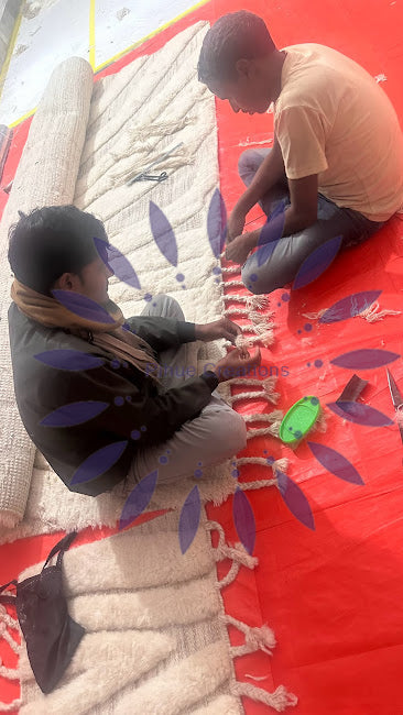 Artisan tying individual knots on a hand-knotted rug loom