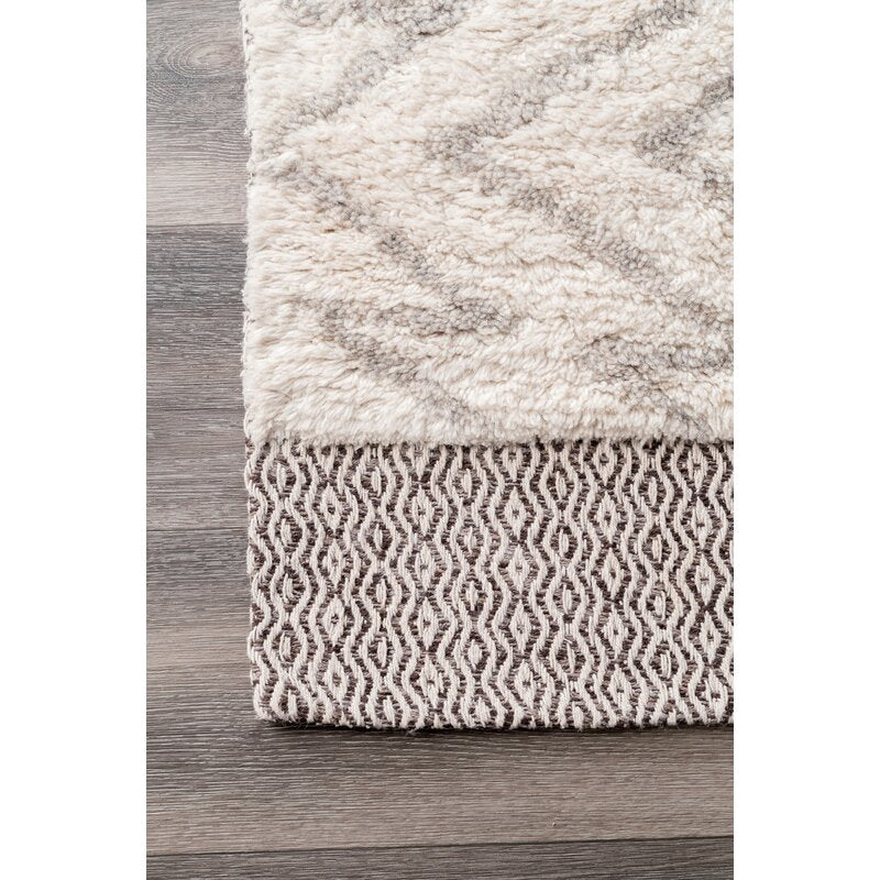 Handwoven ivory shag wool rug with grey diamond pattern and woven brown border - textured high-pile Moroccan style area rug on wood floor